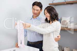 Happy couple holding white onesie