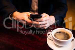 Businessman having a coffee and texting