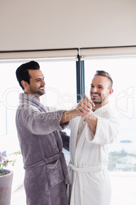 Happy gay couple dancing waltz in bathrobe