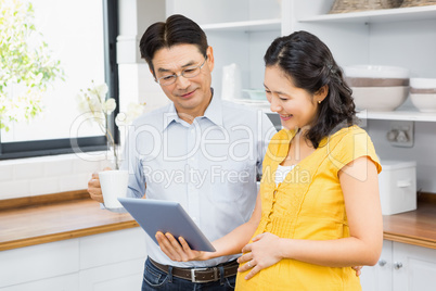 Happy expectant couple using tablet