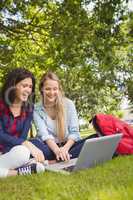 Smiling students using laptop