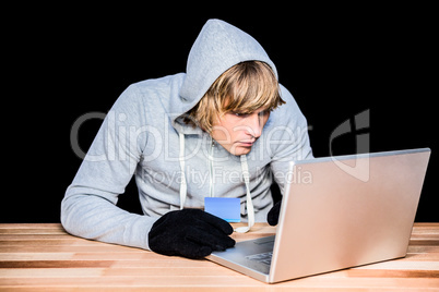 Man in hood jacket hacking a laptop