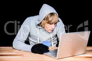 Man in hood jacket hacking a laptop