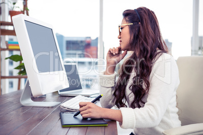 Asian woman using digital board and looking at computer monitor