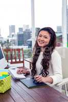 Smiling Asian woman using digital board and computer