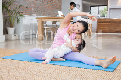 Happy mother and baby daughter exercising on mat