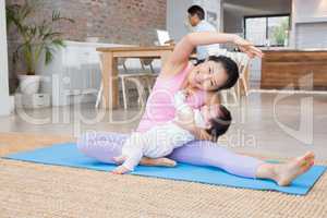 Happy mother and baby daughter exercising on mat