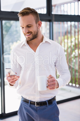Smiling man with mug and smartphone Smiling man with mug and smartphone