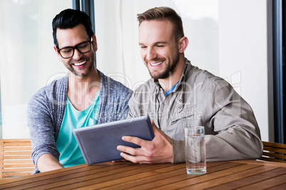 Smiling gay couple using tablet