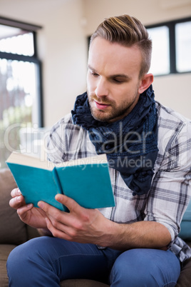 Handsome man reading a book on the couch