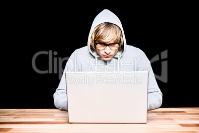 Man in hood jacket hacking a laptop