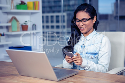 Smiling Asian woman with eyeglasses using smartphone