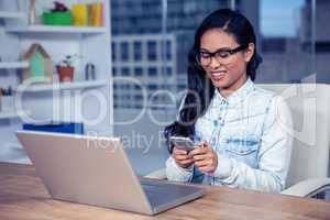 Smiling Asian woman with eyeglasses using smartphone