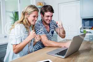 Happy couple watching videos on laptop