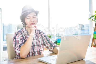 Thoughtful hipster businessman using laptop