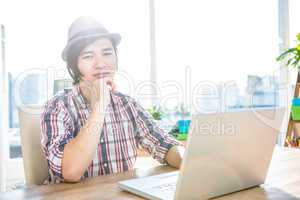 Thoughtful hipster businessman using laptop