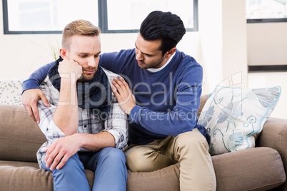 Gay couple comforting each other on the couch