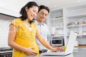 Happy expectant couple using laptop