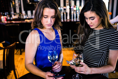 Friends texting and having a glass of wine