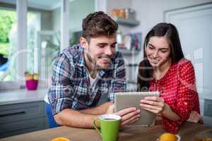 Happy couple having breakfast and using tablet