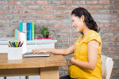 Smiling pregnant woman using laptop