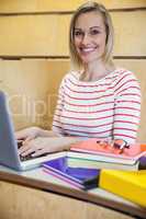 Happy female student typing on laptop