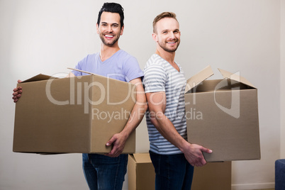 Happy gay couple holding boxes