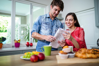 Happy couple having breakfast and reading newspaper