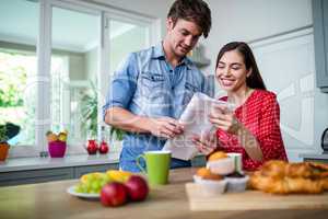 Happy couple having breakfast and reading newspaper