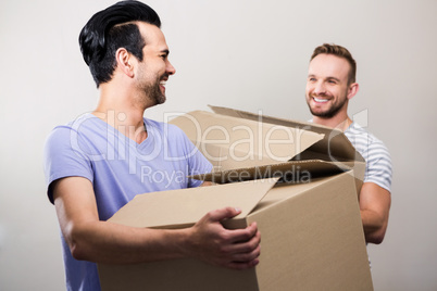 Happy gay couple holding boxes