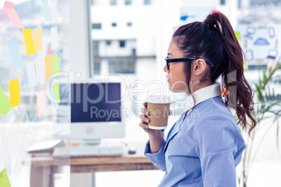 Businesswoman holding disposable cup and looking at wall with no