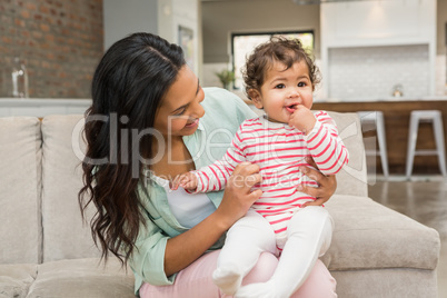 Smiling brunette playing with her baby