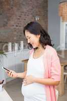 Smiling pregnant woman looking at smartphone