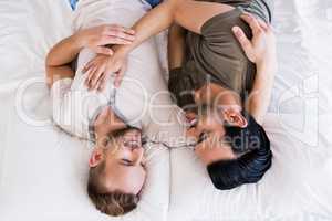 Happy gay couple lying on bed