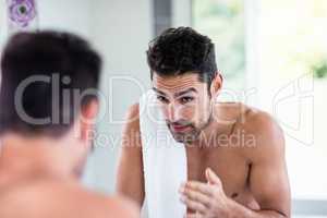 Handsome shirtless man looking in the mirror