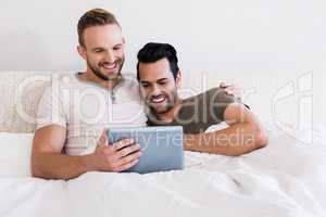 Happy gay couple using tablet