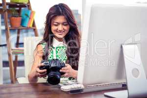 Smiling creative businesswoman holding camera