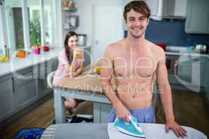 Handsome man ironing in the kitchen