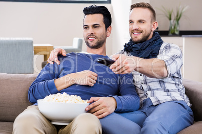Gay couple watching television with pop corn