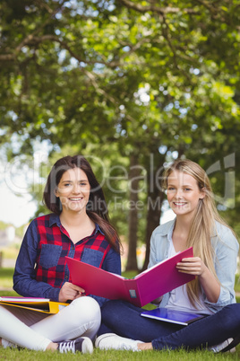 Smiling students holding binder