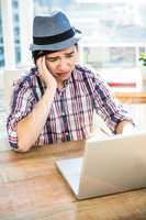 Worried hipster businessman using laptop