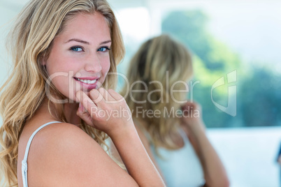 Smiling beautiful young woman looking at herself in the bathroom