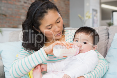 Mother giving milk in bottle to her daughter