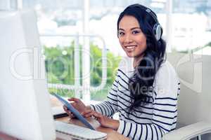 Smiling Asian woman with headphones using tablet