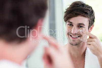 Smiling handsome man applying cream