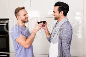 Smiling gay drinking red wine