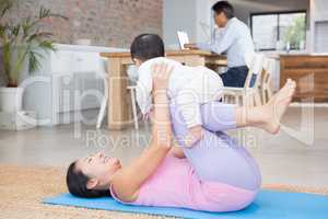 Happy mother and baby daughter exercising on mat