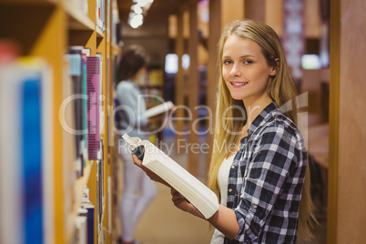 Serious students reading next to bookshelf