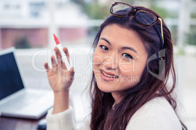 Pretty Asian woman looking at camera holding pen