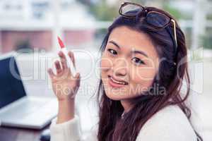 Pretty Asian woman looking at camera holding pen